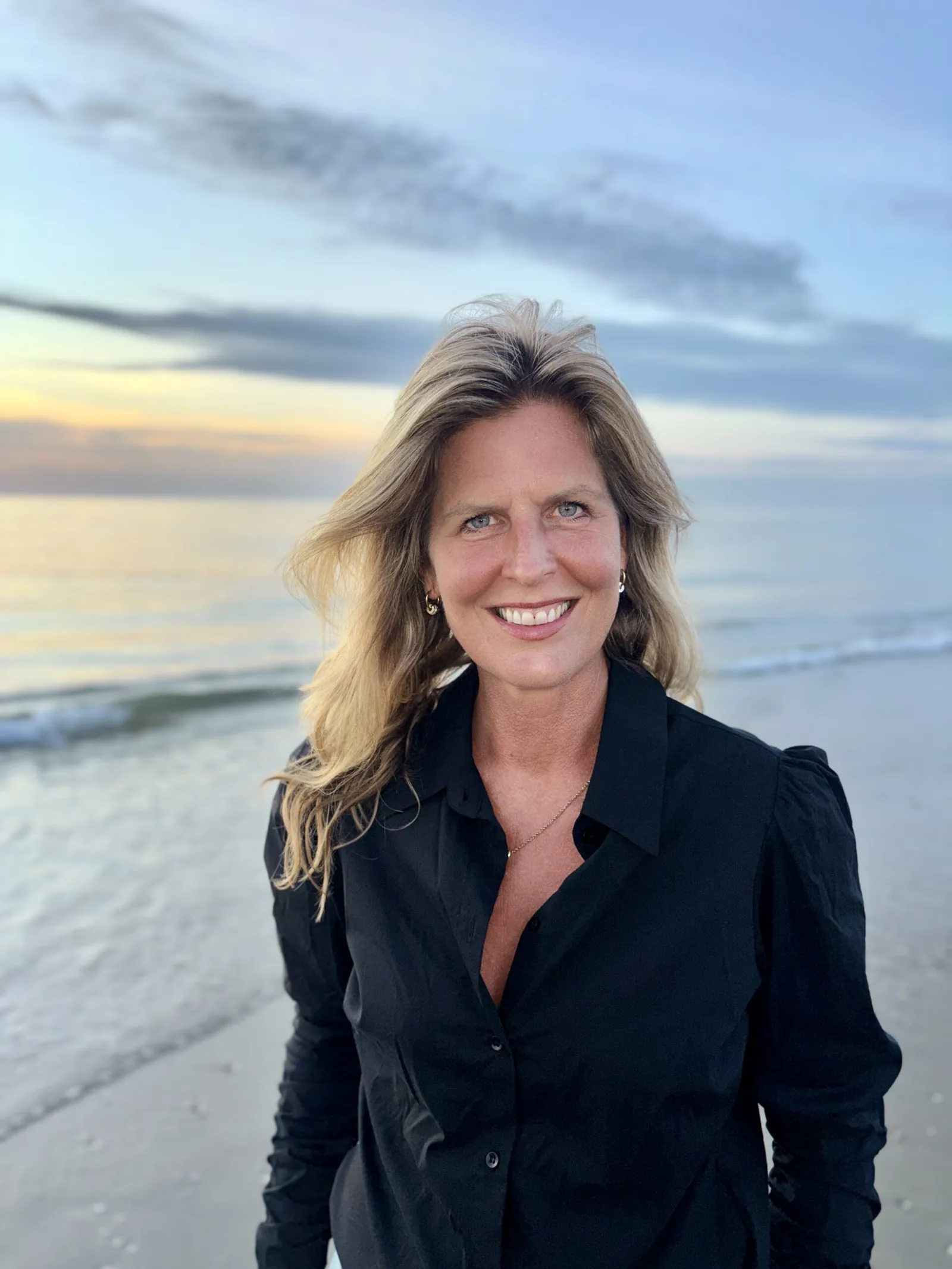 Suzanne de Moor aan zee bij zonsondergang