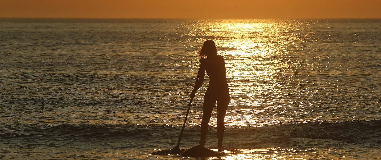 Suzanne op een SUP-board bij zonsondergang
